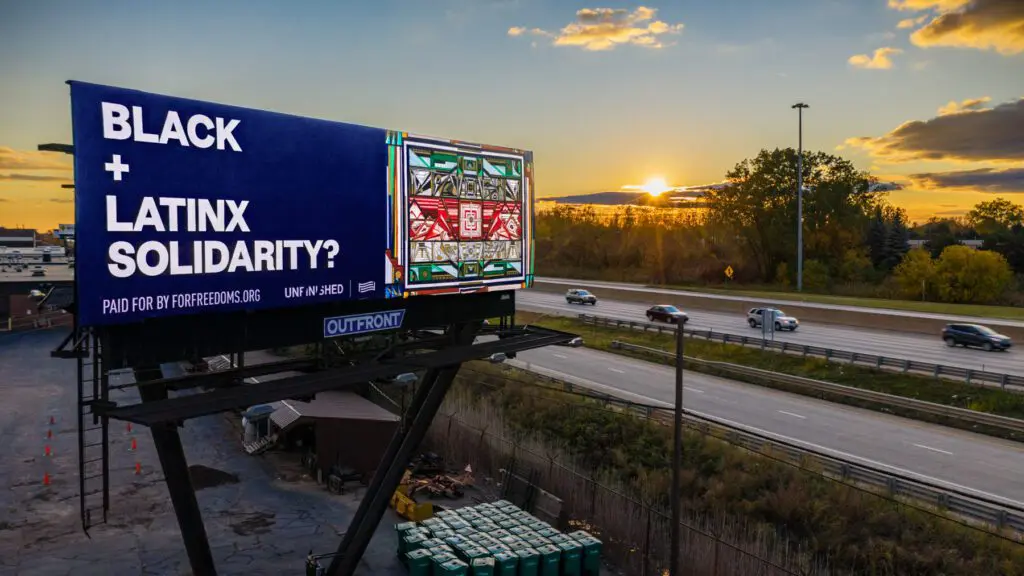 Billboard advertising a Bitcoin tax solidarity message near a highway at sunset.